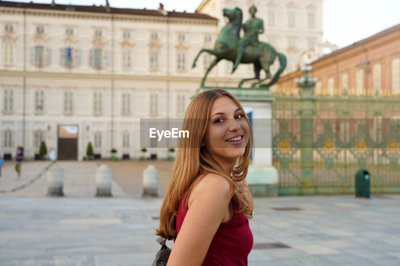 Travel in europe. attractive girl in italy with royal palace of turin on the background.