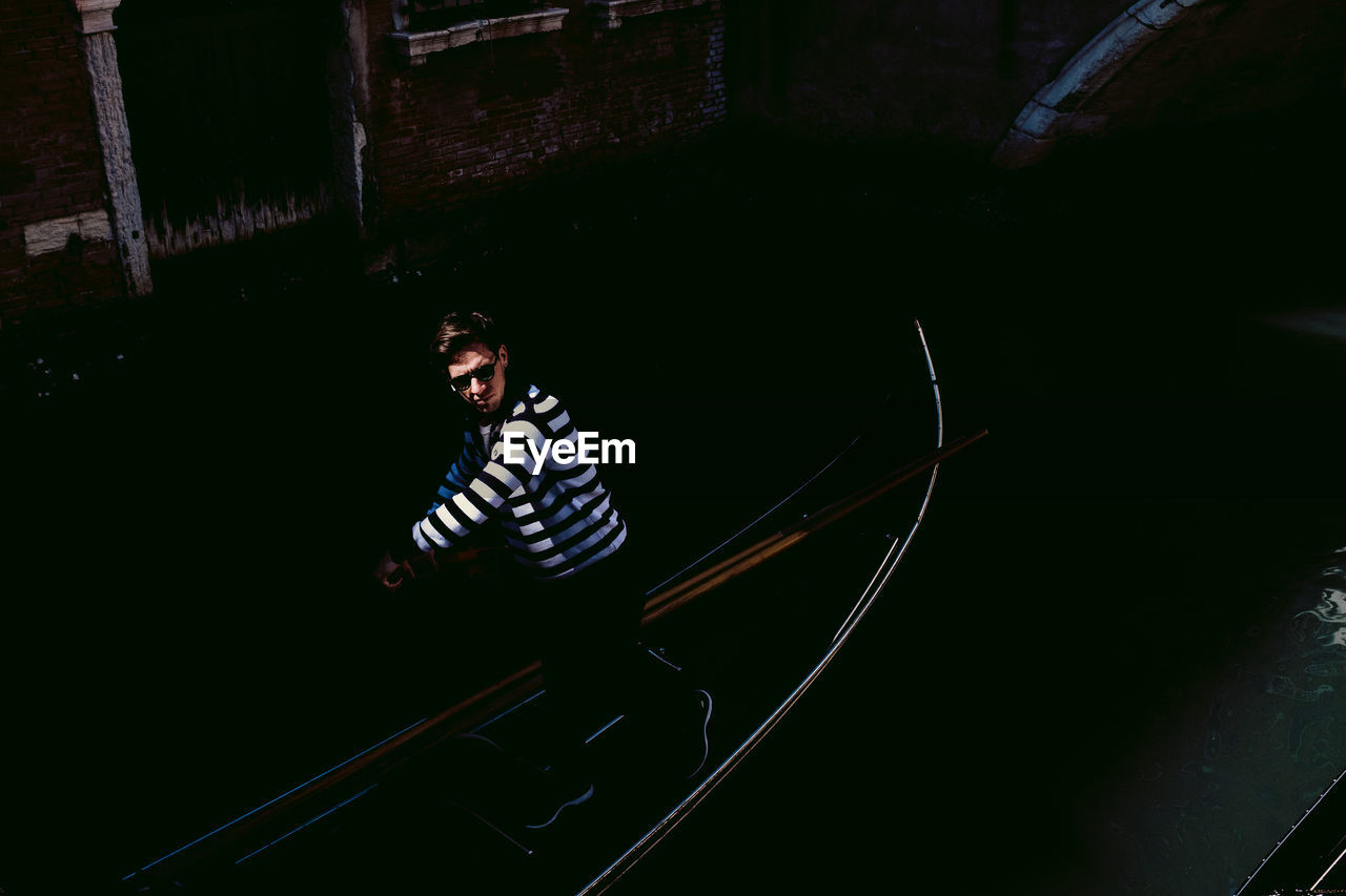 MAN LOOKING DOWN WHILE SITTING ON THE DARK