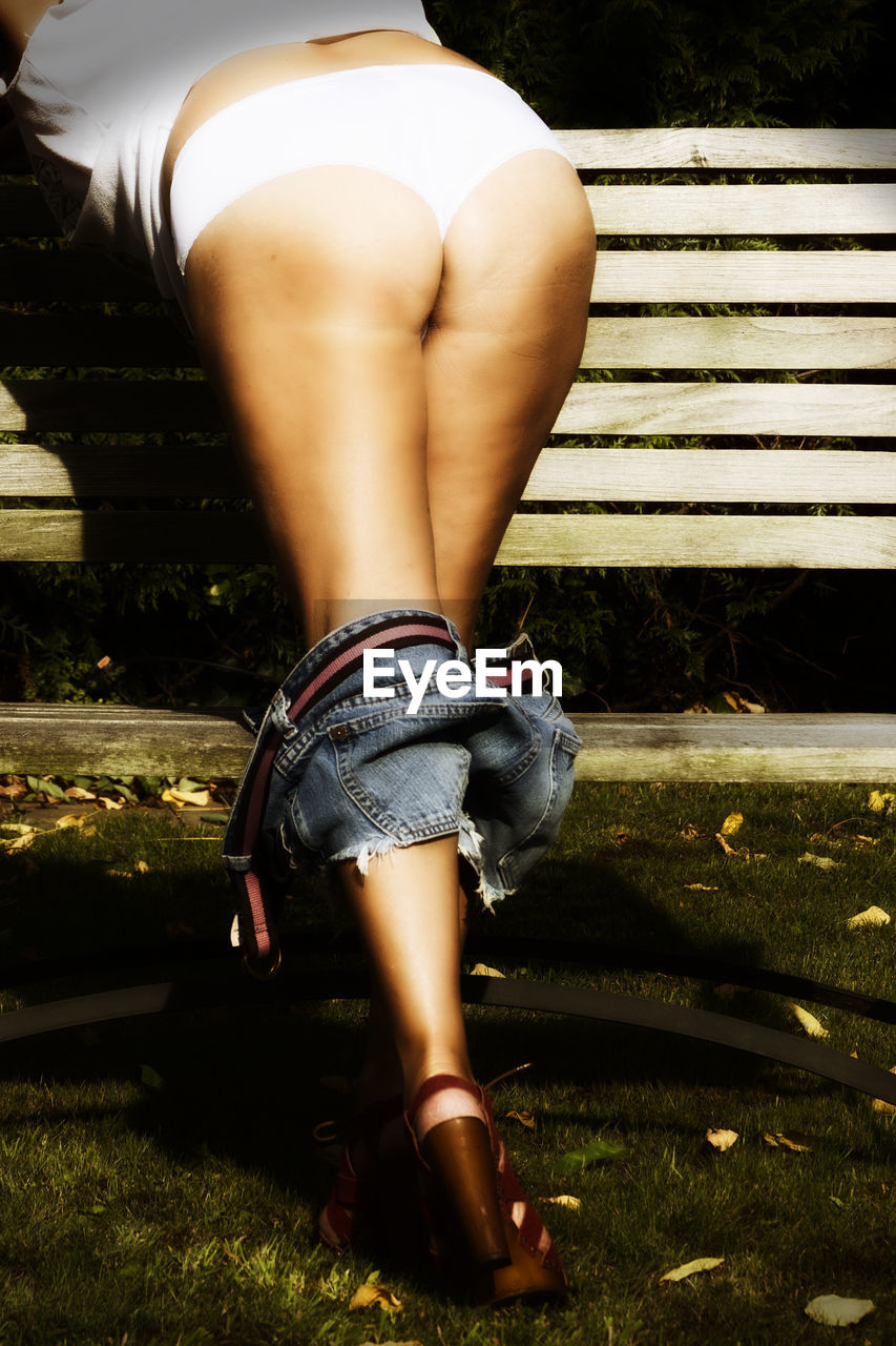 MIDSECTION OF WOMAN IN PARK BENCH