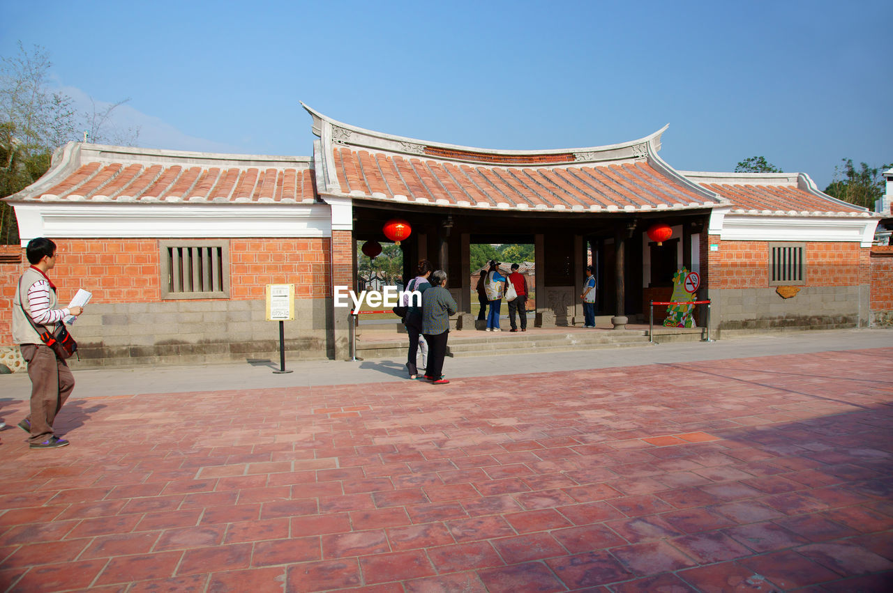 PEOPLE WALKING ON FOOTPATH AGAINST BUILDING