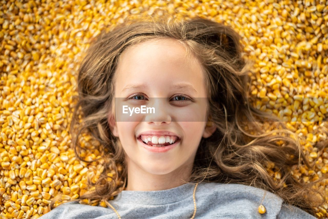 Portrait of smiling girl lying on corn kernel