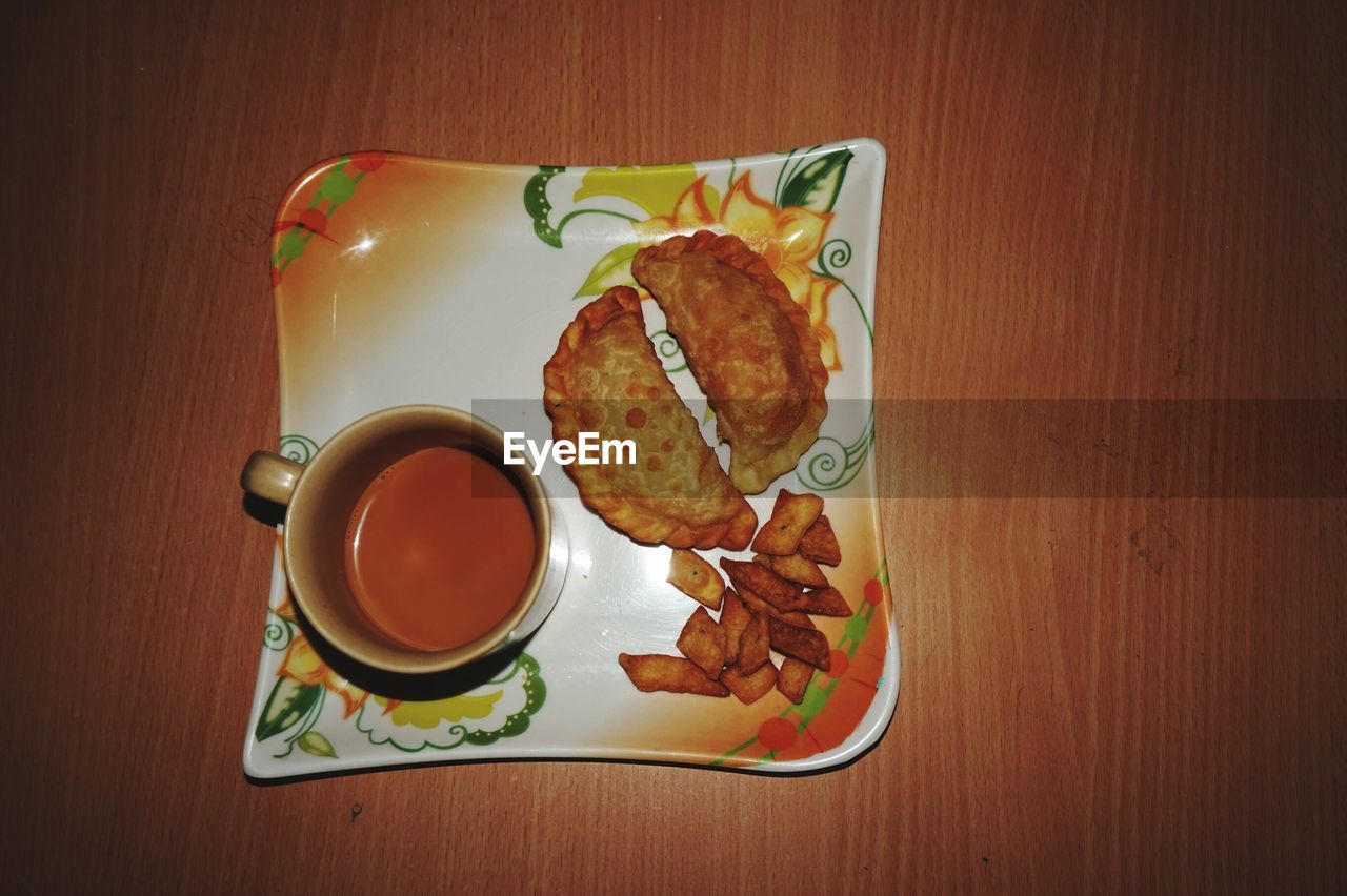 High angle view of tea and snacks in plate on table