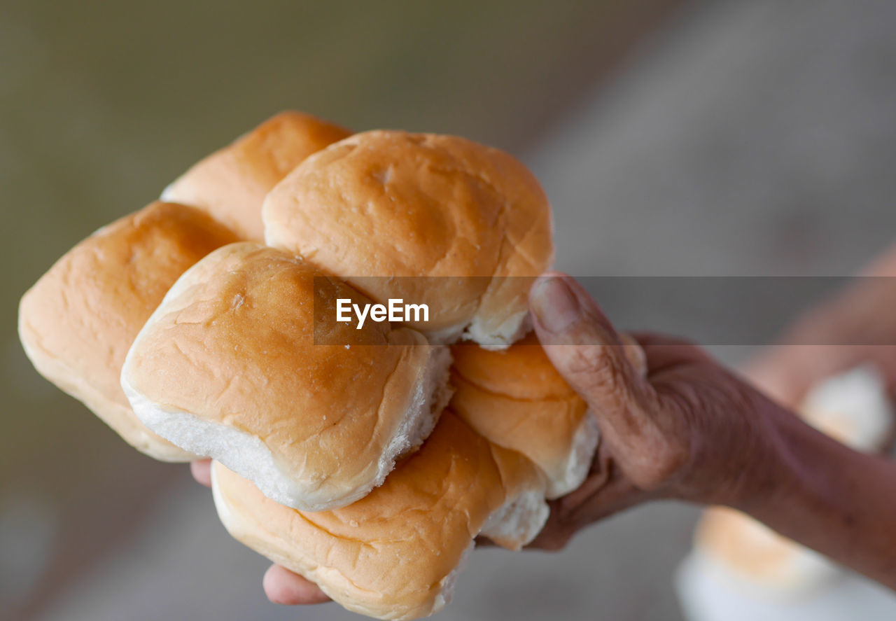 CLOSE-UP OF PERSON HAND HOLDING BREAD