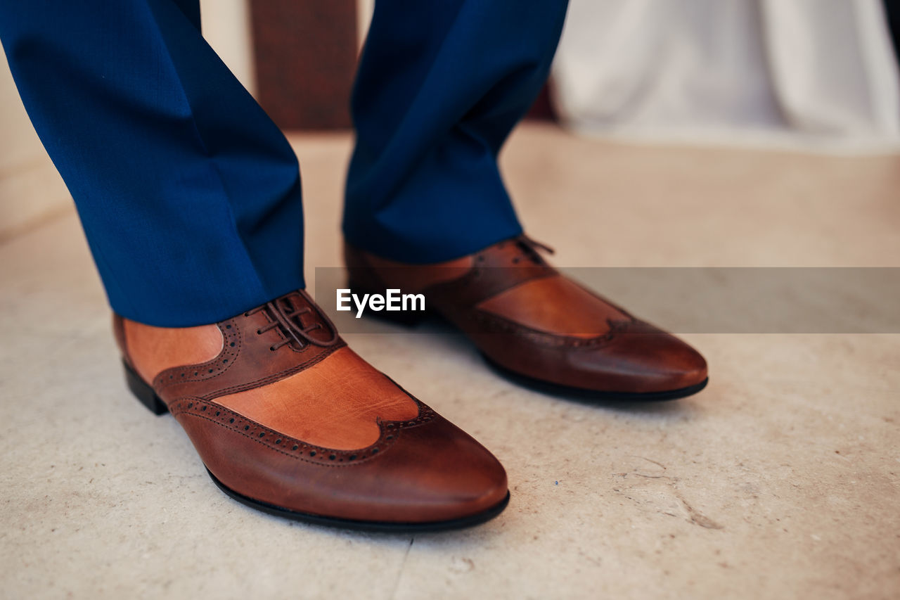 Low section of person wearing shoes standing on tiled floor