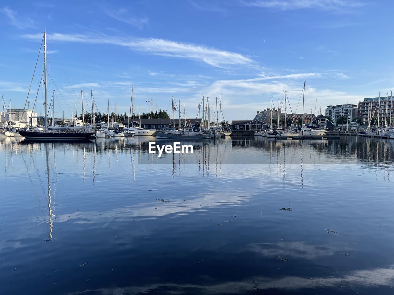 water, marina, nautical vessel, reflection, dock, transportation, sky, sailboat, mode of transportation, harbor, sea, ship, cloud, nature, moored, mast, no people, pole, architecture, vehicle, blue, boat, travel destinations, day, travel, bay, outdoors, beauty in nature, tranquility, port, city, building exterior, yacht, sailing, waterfront, built structure, pier, scenics - nature, tranquil scene, watercraft, sailing ship