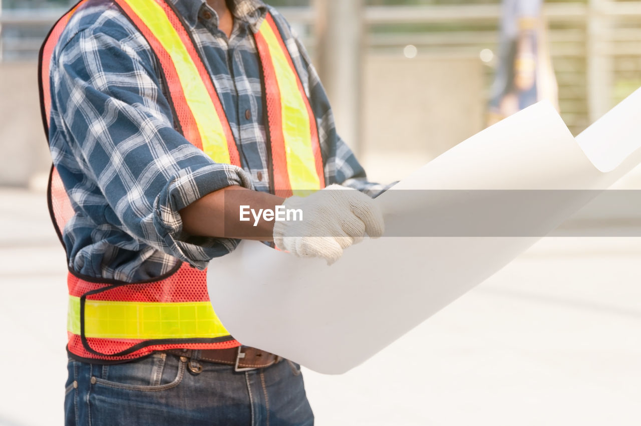 MIDSECTION OF MAN WORKING ON CONSTRUCTION SITE