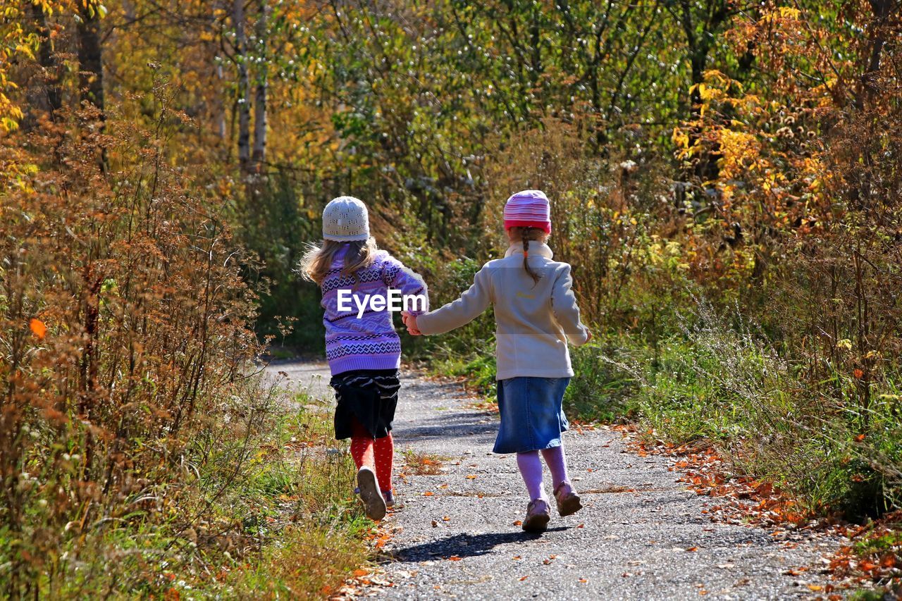 Rear view of girls running on footpath