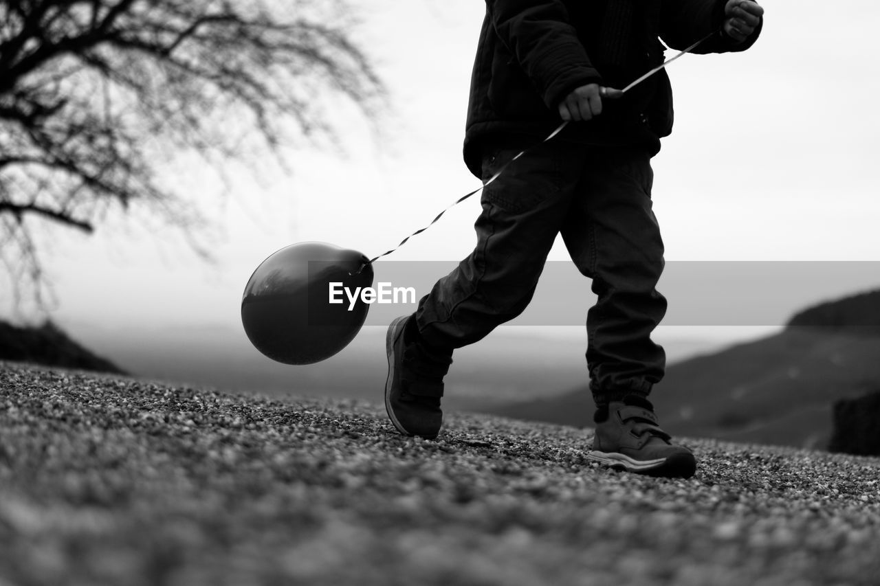 Surface level view of boy walking with balloon on road