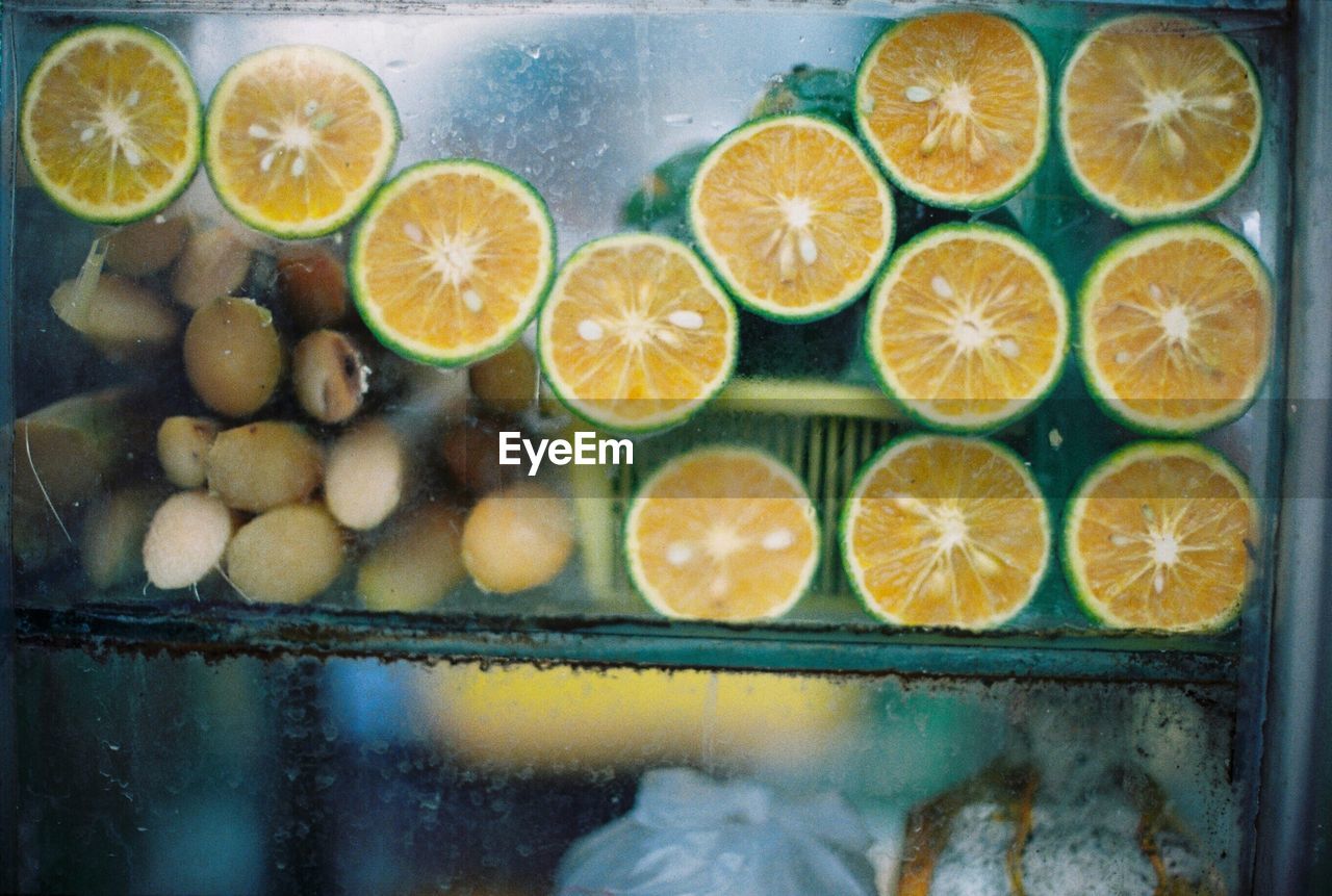 Sliced citrus fruits behind transparent surface