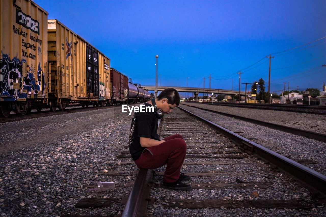 MAN SITTING ON RAILROAD TRACK