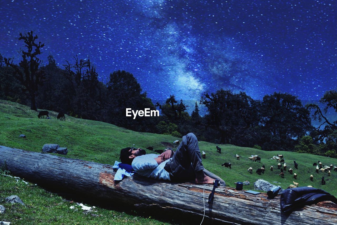 PEOPLE SITTING ON LAND AGAINST STAR FIELD