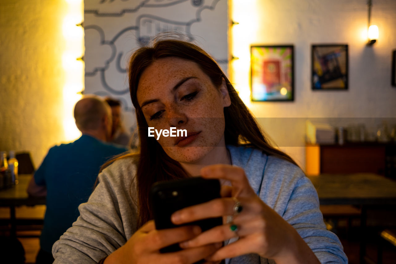 PORTRAIT OF MATURE MAN USING MOBILE PHONE IN RESTAURANT