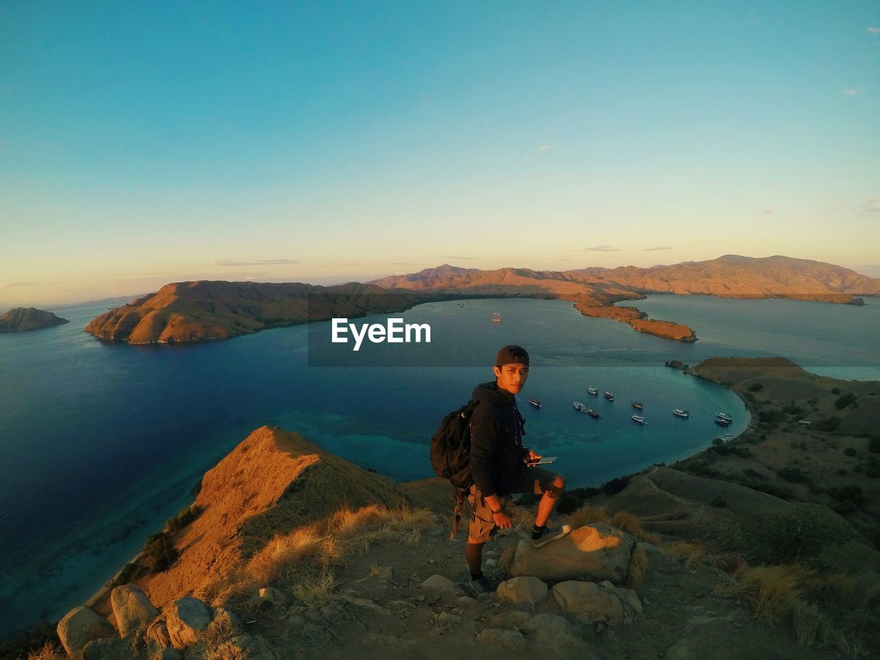 Portrait of young man standing on rock against sea and sky