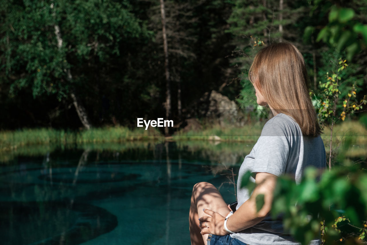 Woman sitting by lake in park