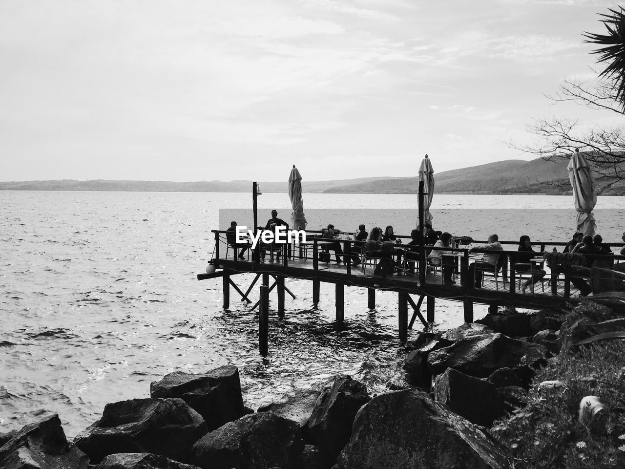 People on jetty against calm sea