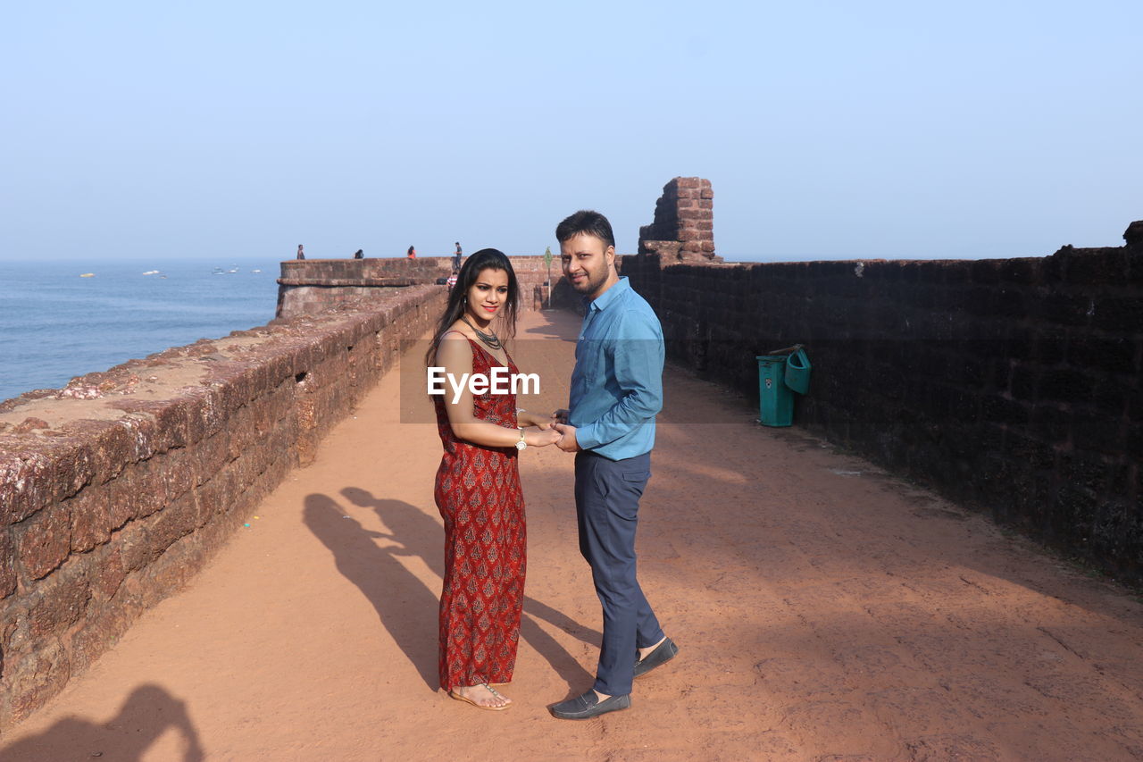 Couple standing at fort by sea against sky