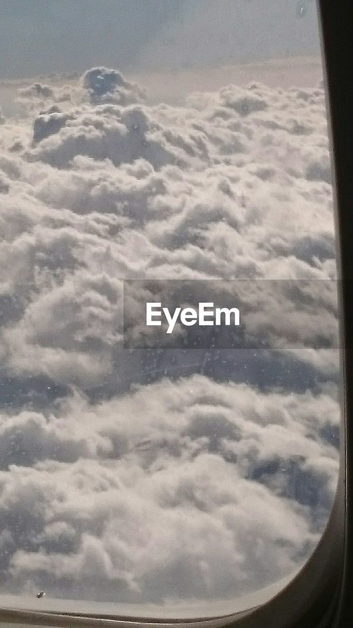 AERIAL VIEW OF CLOUDSCAPE OVER AIRPLANE WINDOW