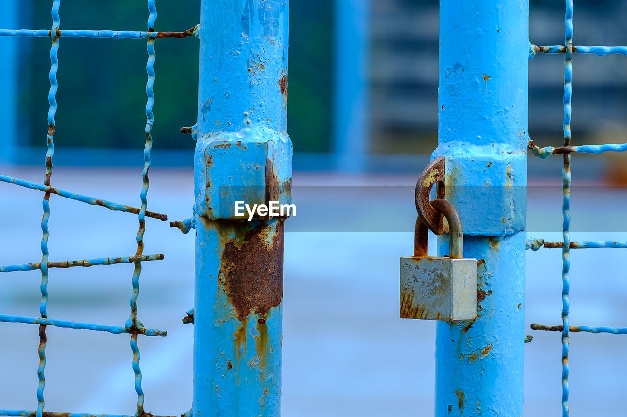 Close-up of padlock hanging on rusty fence