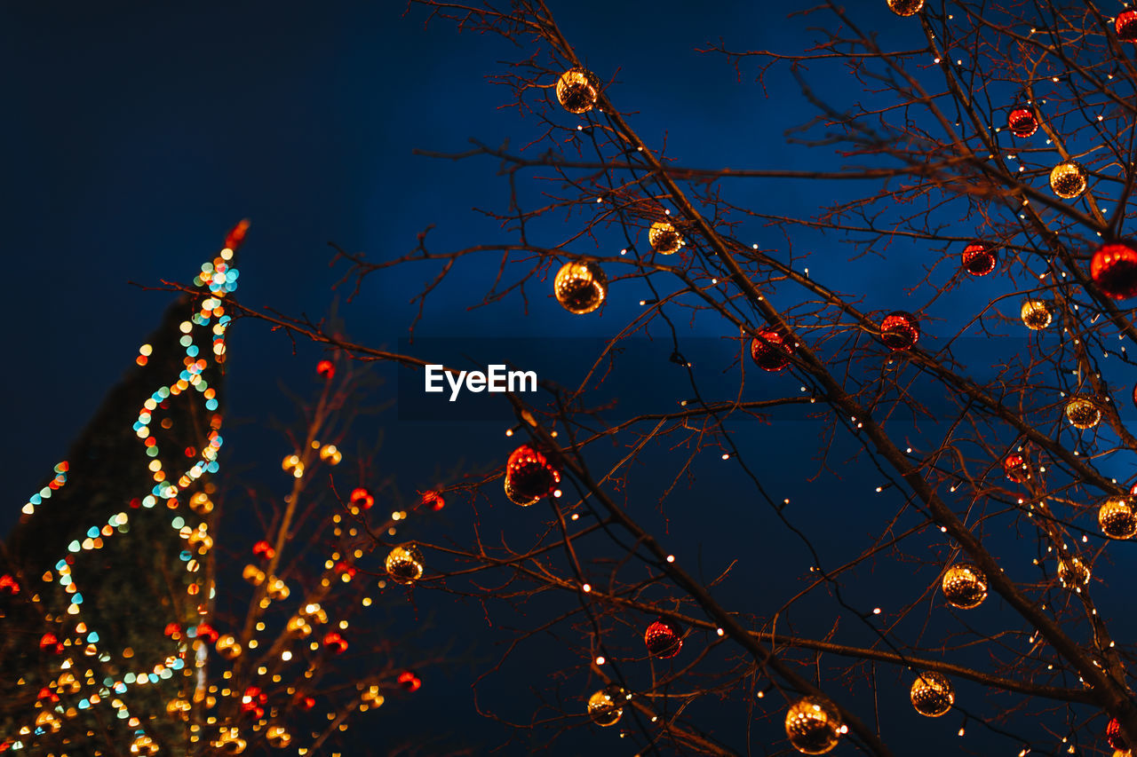 Tree branches decorated with christmas red and gold glittering balls. new year's outdoor decorations