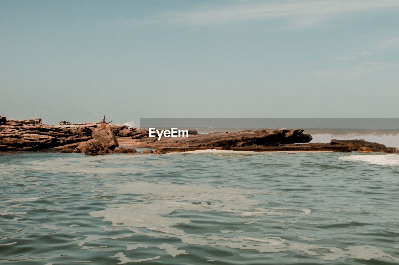 ROCKS ON SHORE AGAINST SKY