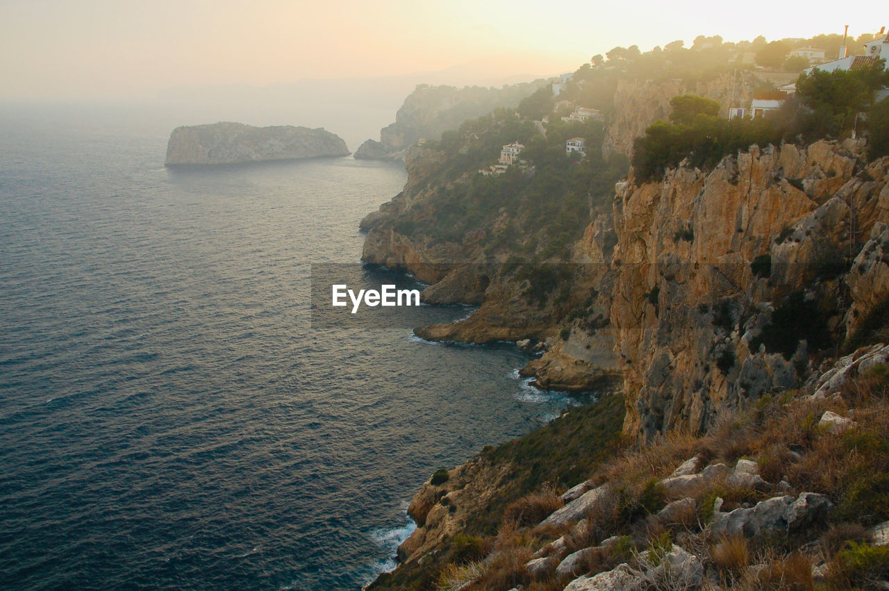 Scenic view of sea and rocky coastline against sky