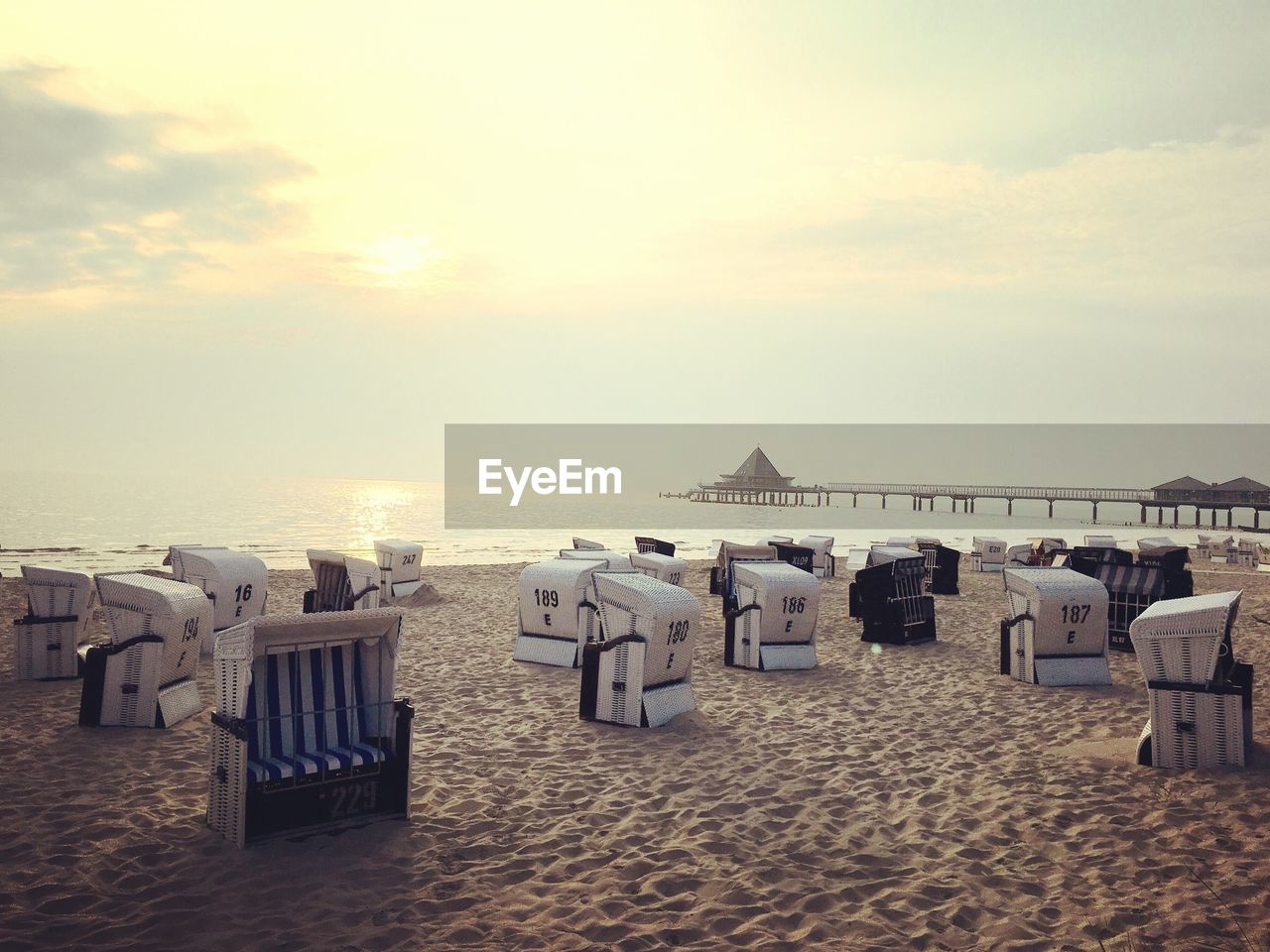 Hooded chairs at beach against sky