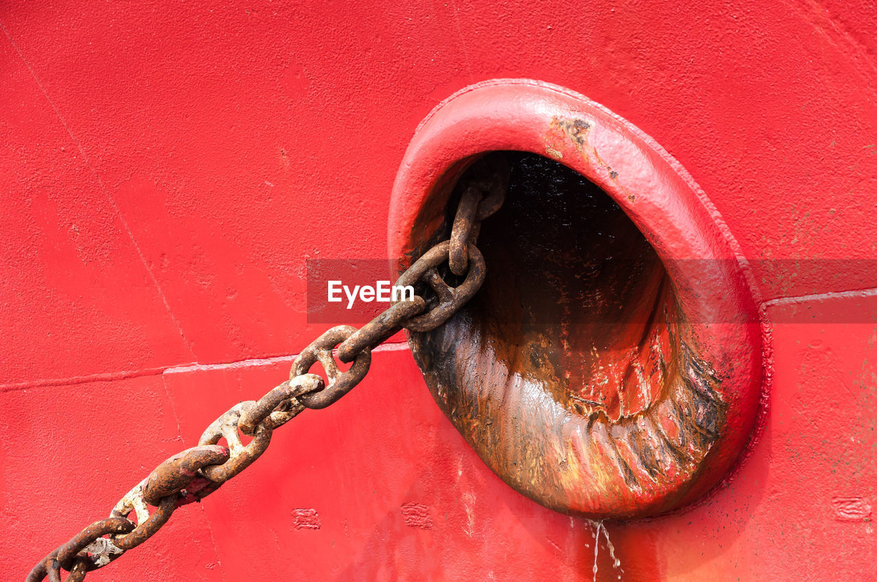 Close-up of rusty chain of red fishing boat