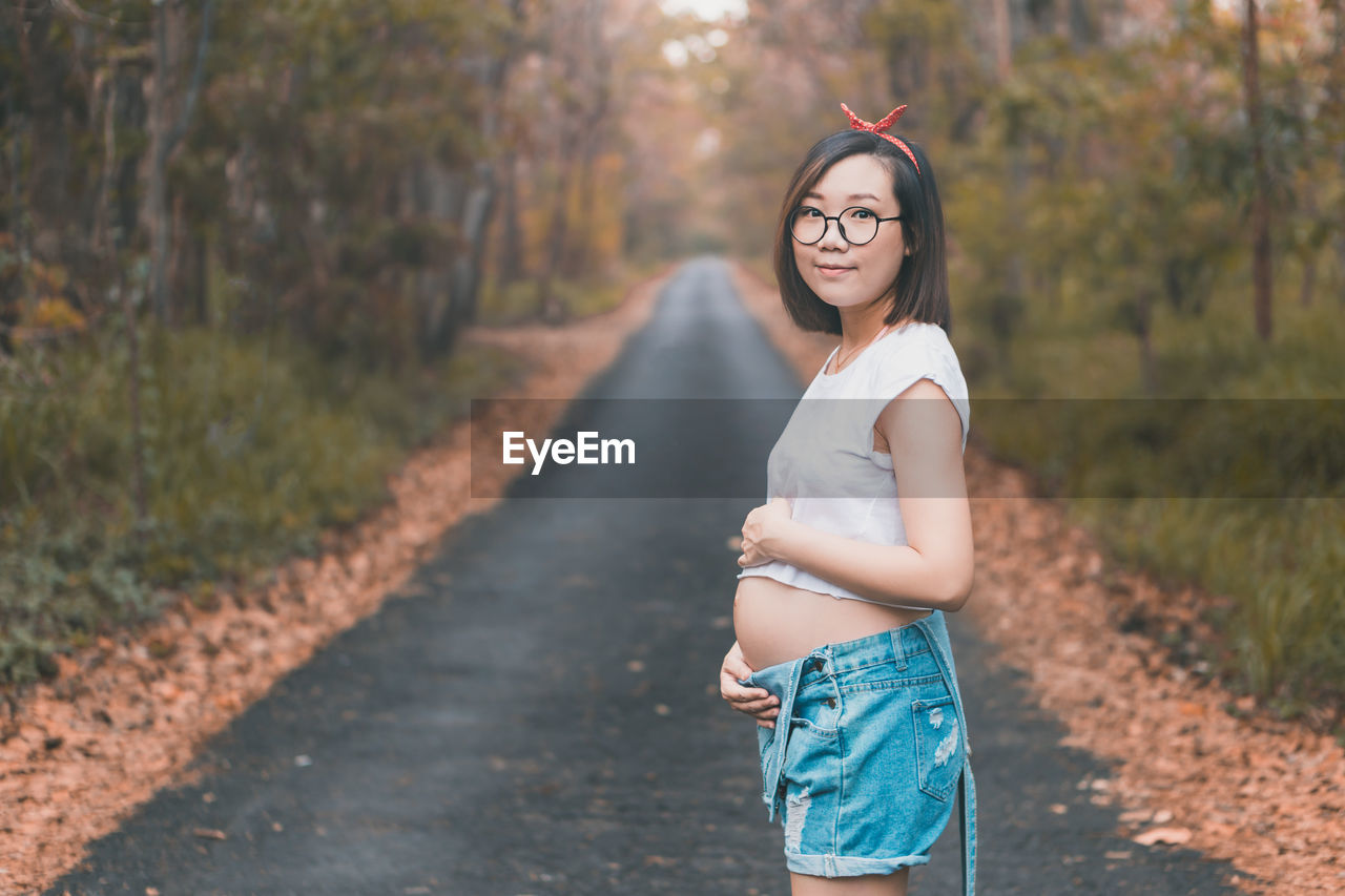 Young pregnant asian woman wearing cute clothes and glasses