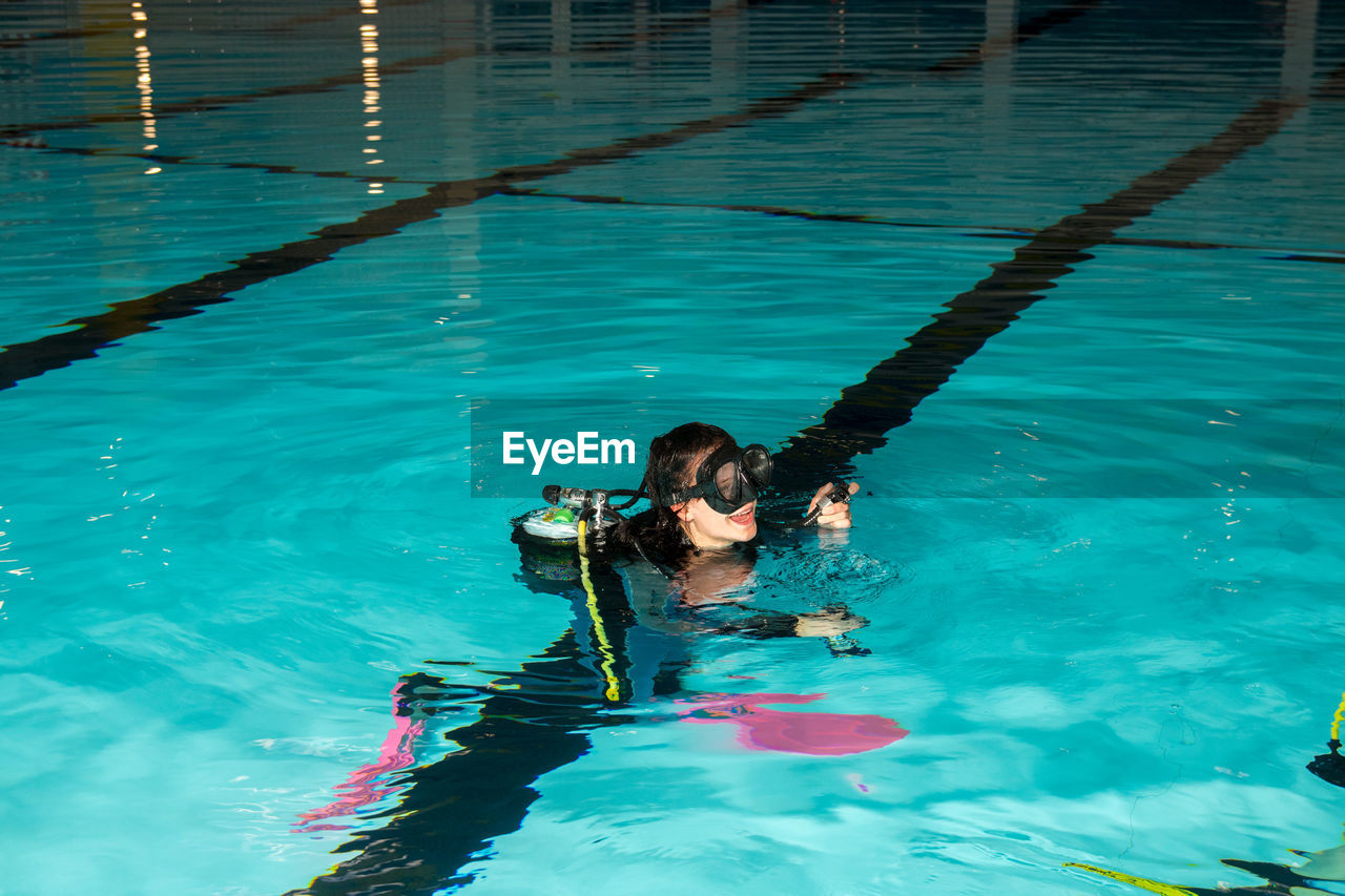 Young woman scuba diving in swimming pool