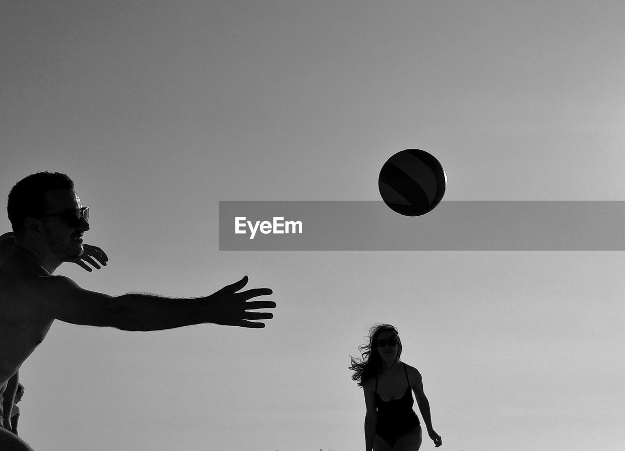 Woman playing with ball against clear sky