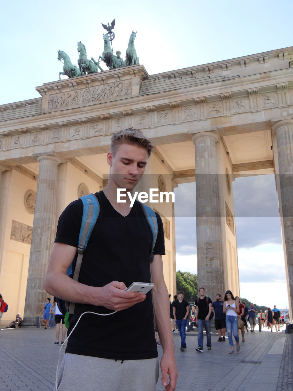 Man using phone while standing in front of brandenburg gate