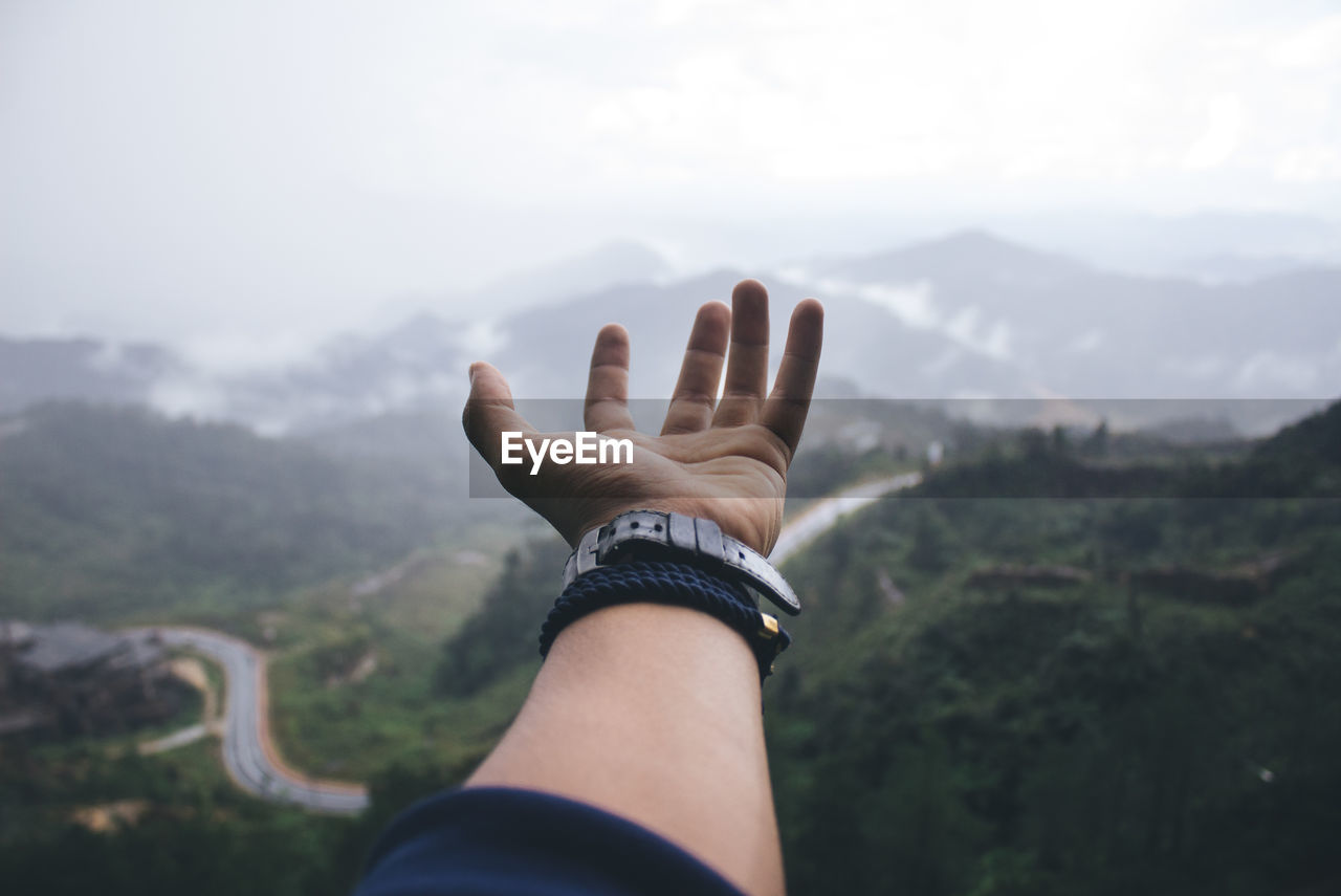 Close-up of human hand against mountain