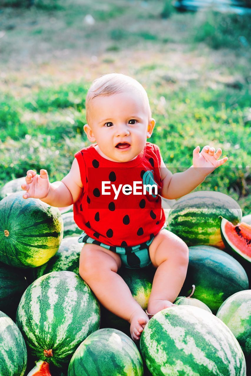 Portrait of cute baby boy sitting over watermelons