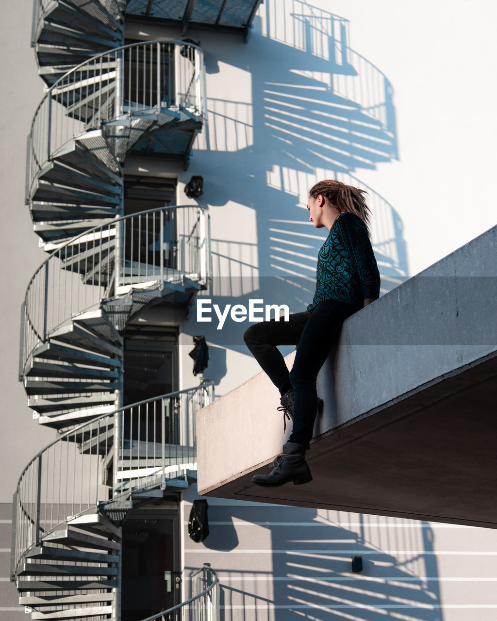 Low angle view of woman sitting against building