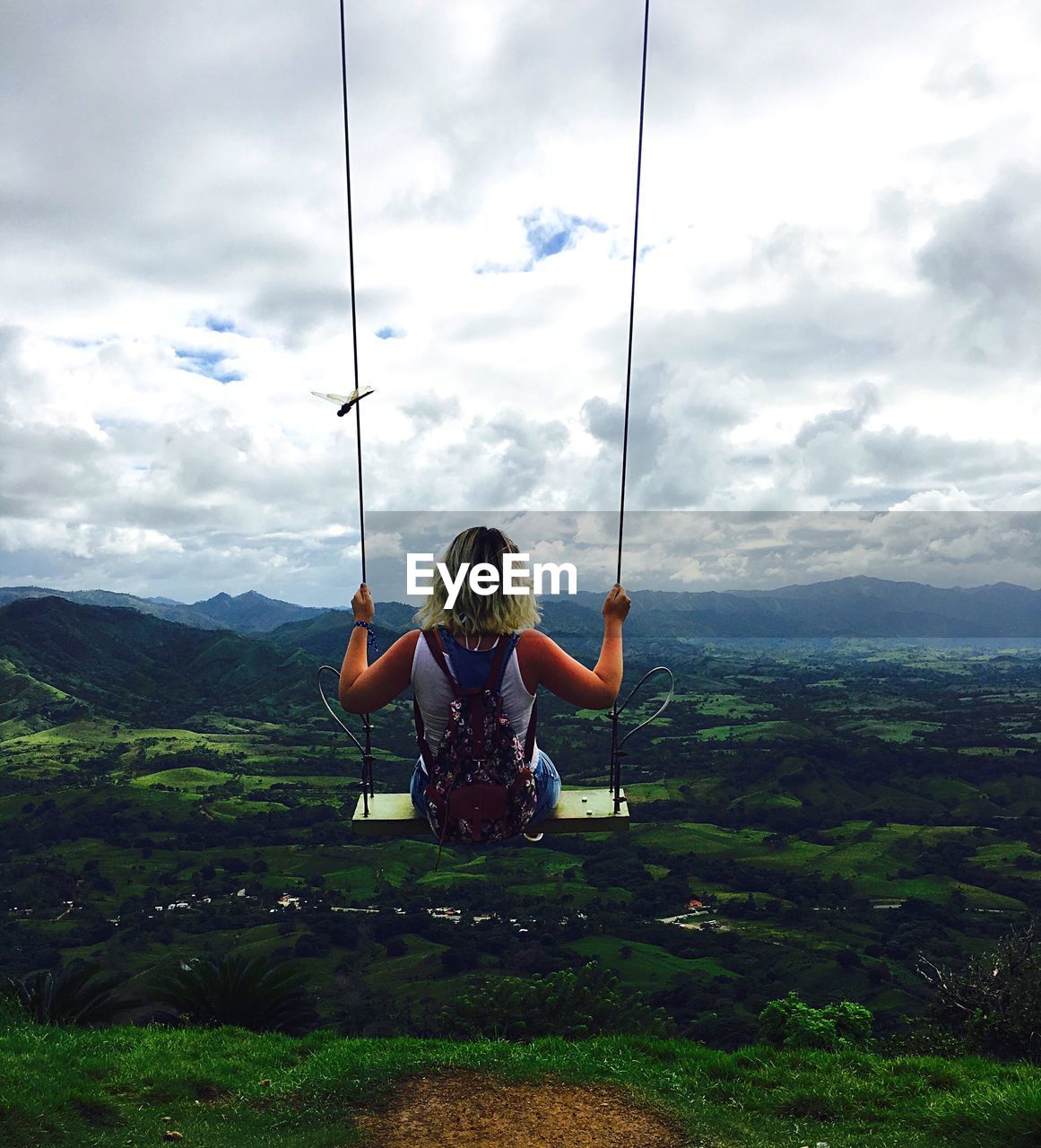 REAR VIEW OF BOY SITTING ON SWING