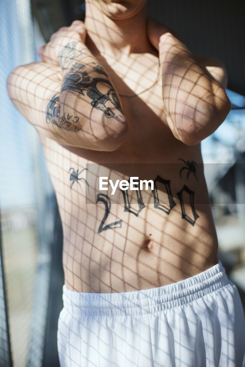 Midsection of shirtless man with tattoo