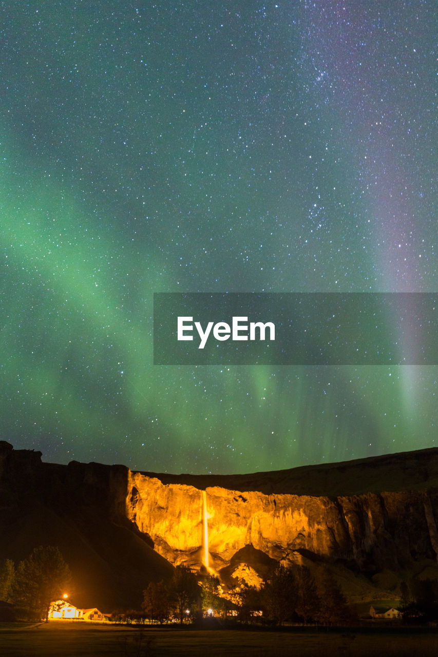 Scenic view of aurora borealis and milky way against starry sky over mountains at night