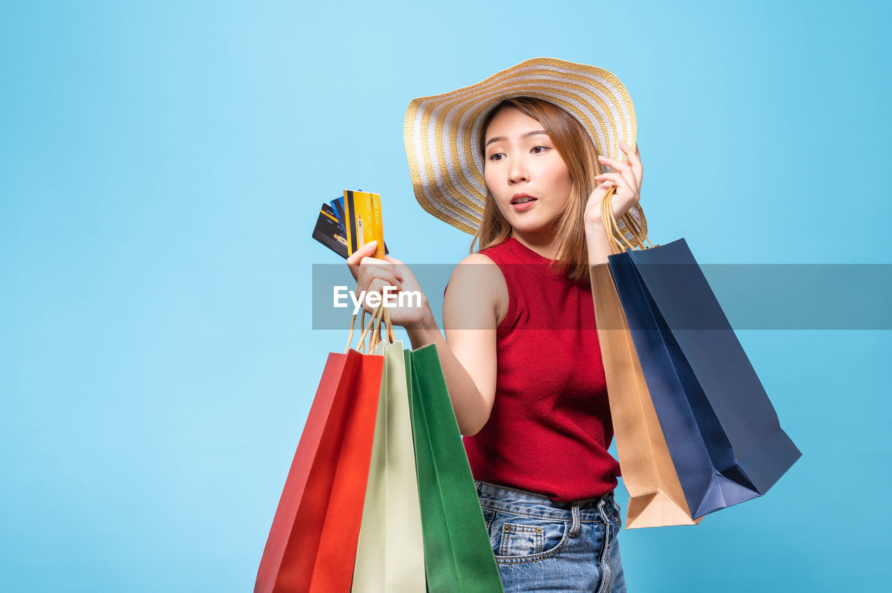 YOUNG WOMAN WEARING HAT AGAINST BLUE BACKGROUND