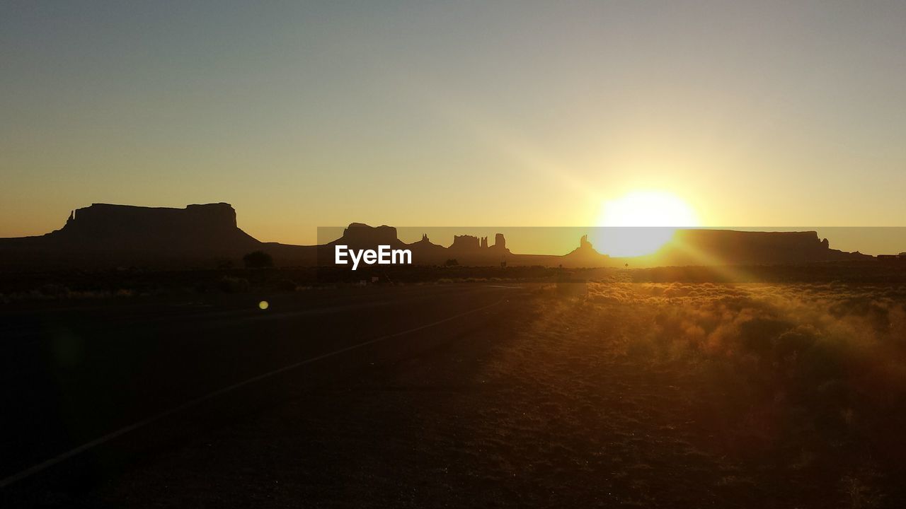 Silhouette landscape against clear sky during sunset