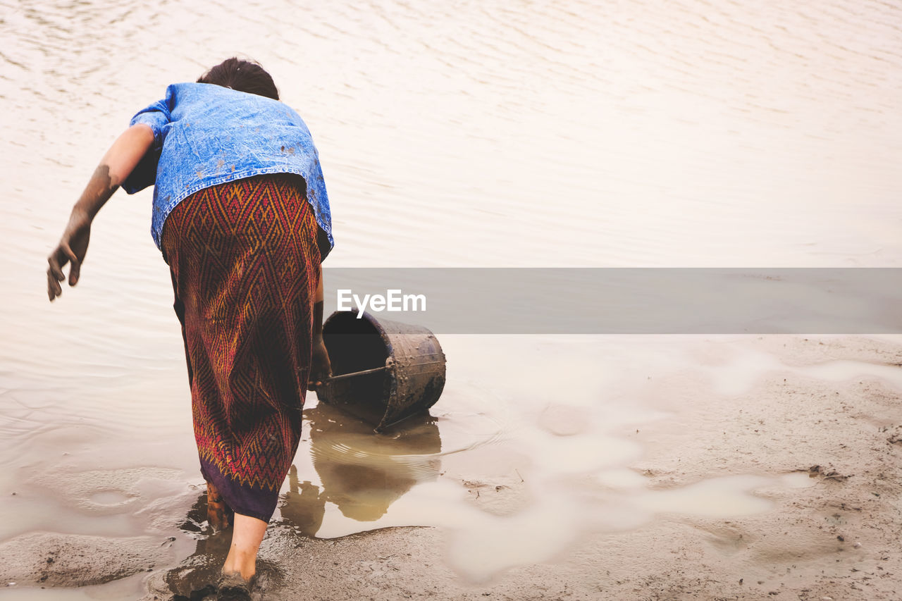 Rear view of girl with bucket at lakeshore