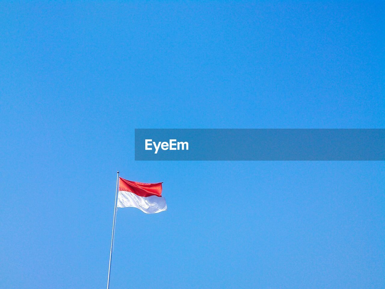 LOW ANGLE VIEW OF FLAGS AGAINST CLEAR BLUE SKY