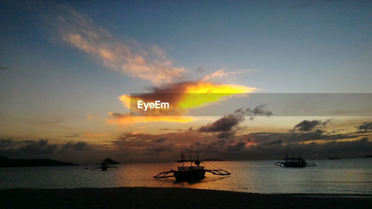 Boats in sea at sunset