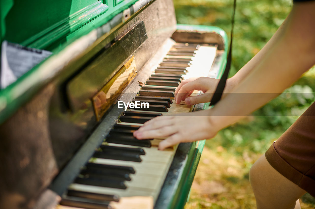 cropped hand of man playing piano