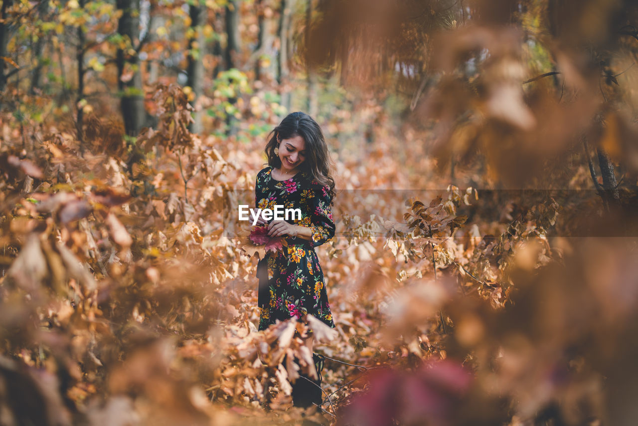 Portrait of young woman standing on field during autumn