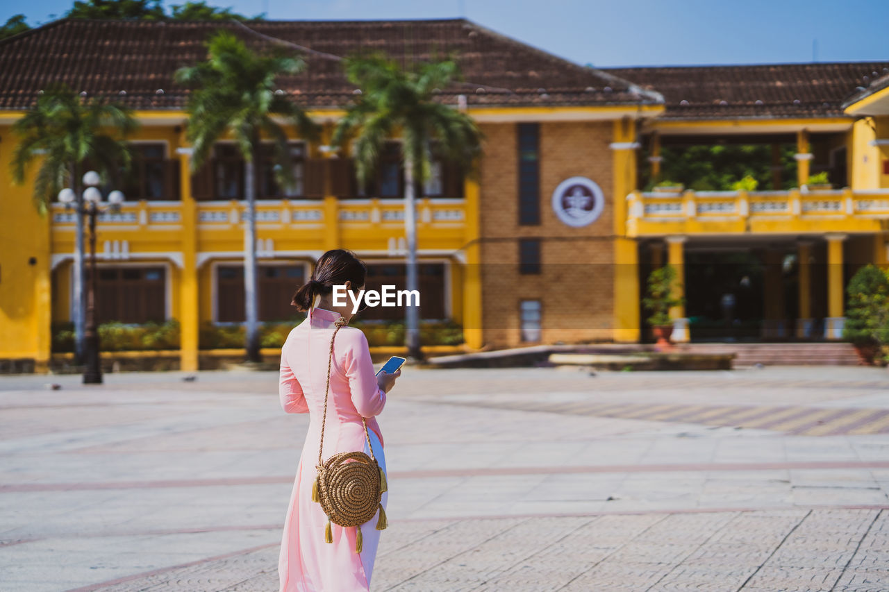 Woman using phone while standing outdoors