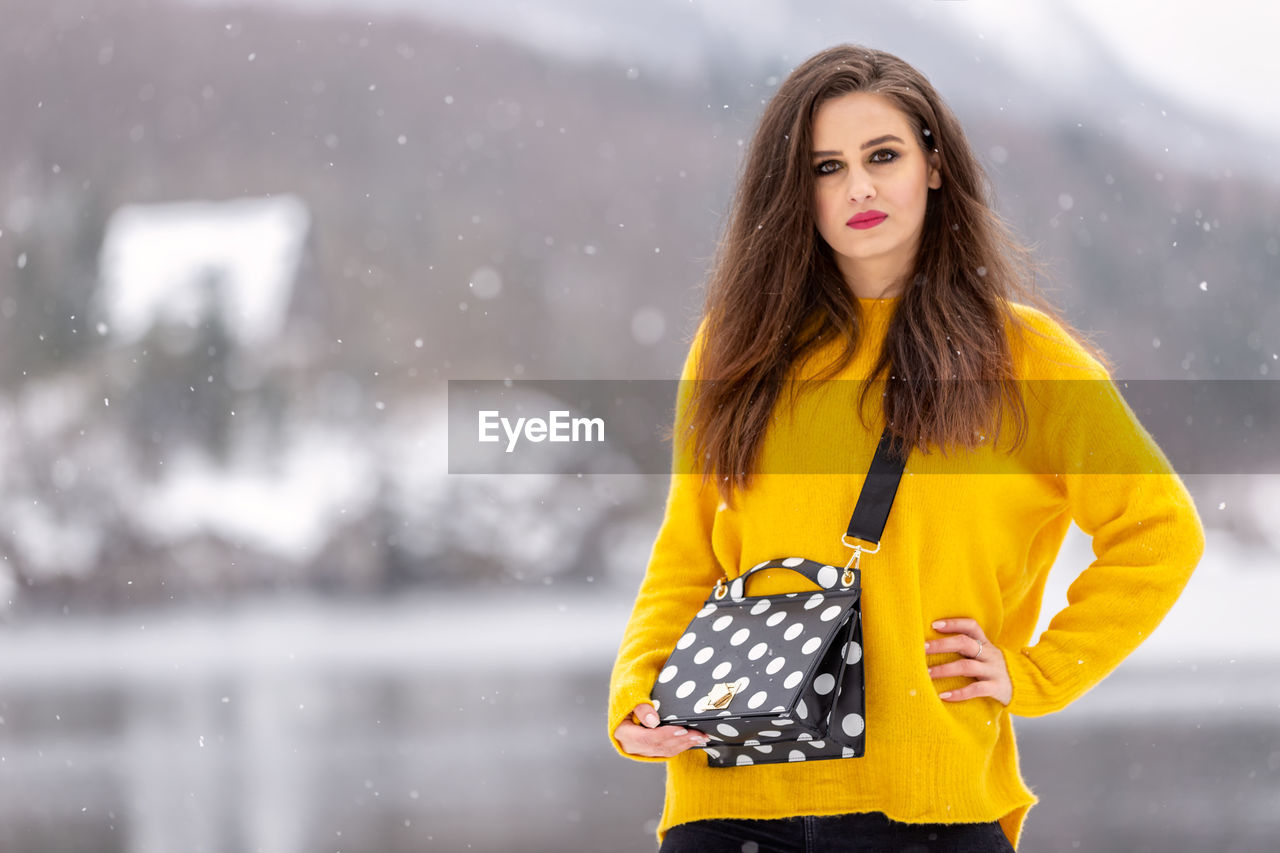 Portrait of woman standing outdoors during snowfall