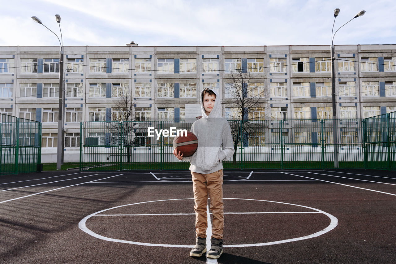 Full length of boy standing on basketball field