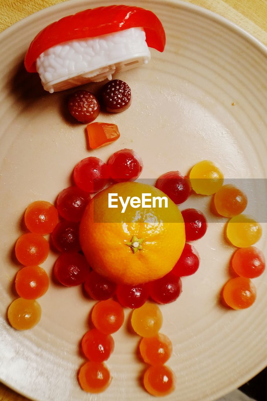 Directly above shot of orange and candies in plate