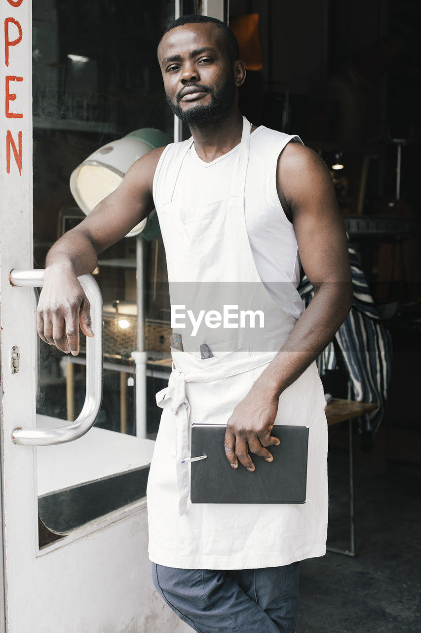 Portrait of male shop owner standing at entrance