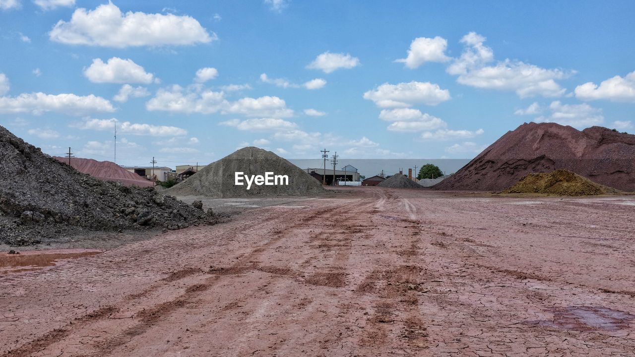 Dirt road at open-pit mine against sky